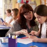 Teacher supporting a pupil to build self esteem and confidence and in the classroom